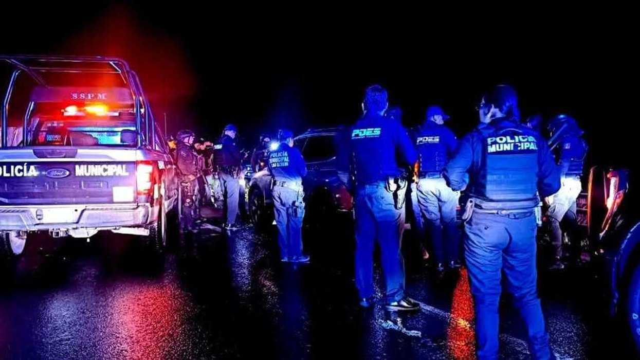 Elementos de la Policía Estatal y Policía Municipal reunidos junto a vehículos con luces de emergencia durante un operativo nocturno en carretera