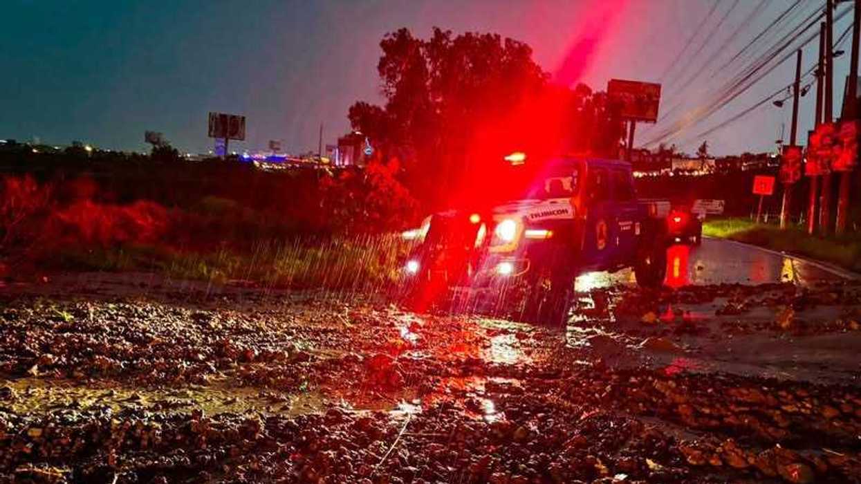 Elementos de Protección Civil de El Marqués con trajes impermeables junto a una ambulancia durante operativo nocturno