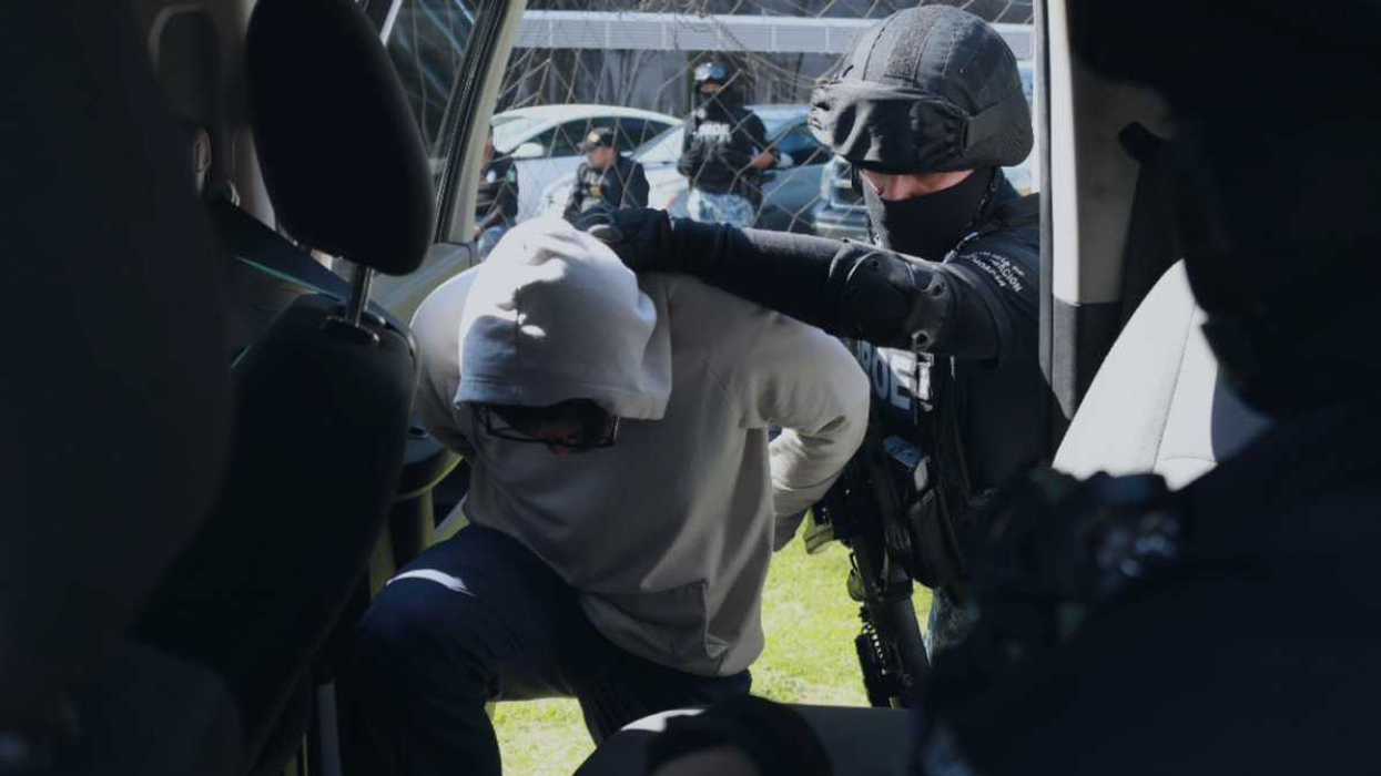 Elementos de una unidad táctica de la Fiscalía de Michoacán trasladan a un hombre detenido hacia un vehículo oficial en La Piedad