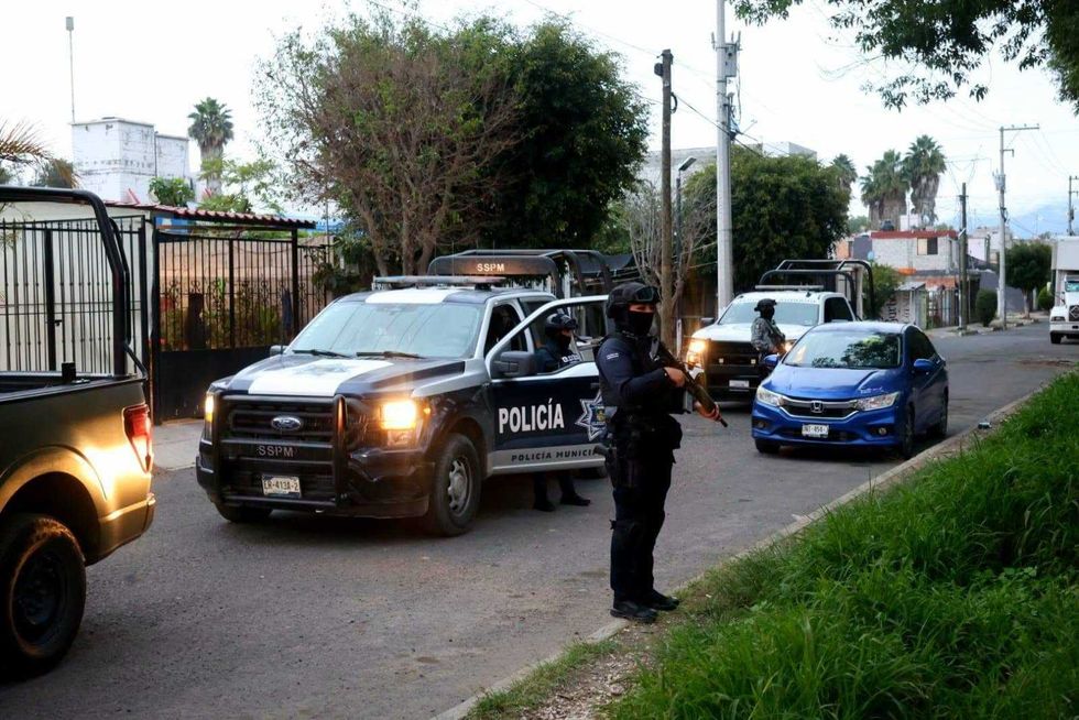 Elementos del Ej\u00e9rcito y la Polic\u00eda Municipal junto a un autom\u00f3vil rojo en una calle de San Juan del R\u00edo durante operativos