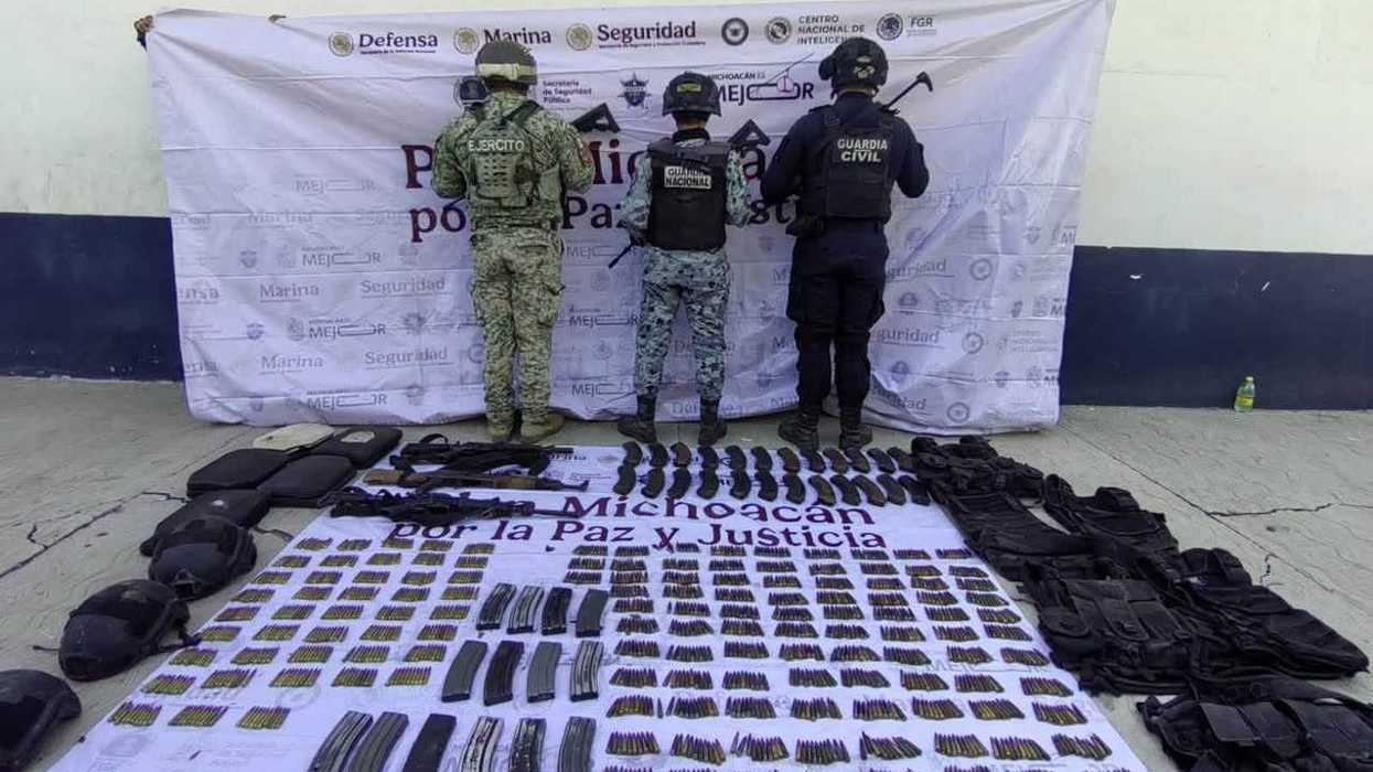 Elementos del Ejército, Guardia Nacional y Guardia Civil de espaldas frente a una lona institucional, con armamento, cargadores, cartuchos y equipo táctico exhibidos en el suelo