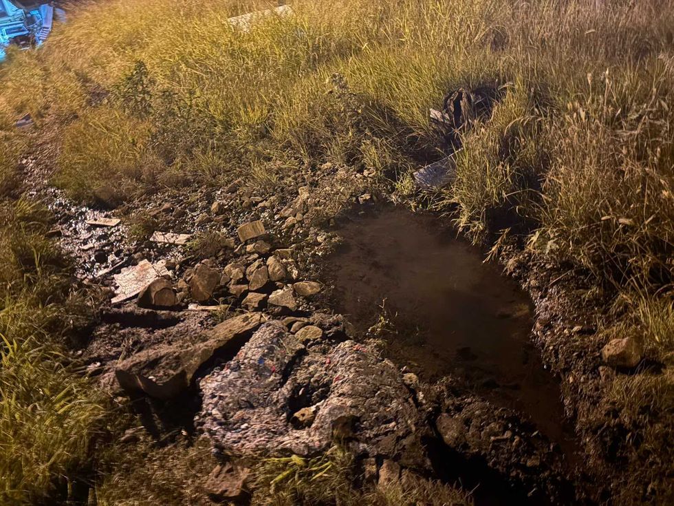 Encharcamiento y tierra removida entre piedras y pasto en el punto de la fuga de agua del predio de avenida R\u00edo Moctezuma, en San Juan del R\u00edo