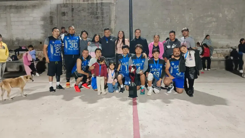 Equipo varonil con uniforme azul posa con trofeo y medallas junto a familiares tras la premiaci\u00f3n en Urecho