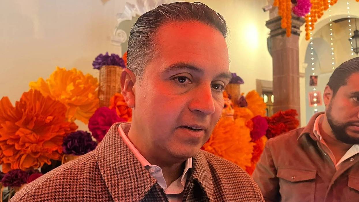 Eric Gudiño Torres, Secretario de Gobierno Estatal, habla durante una entrevista frente a adornos de Día de Muertos