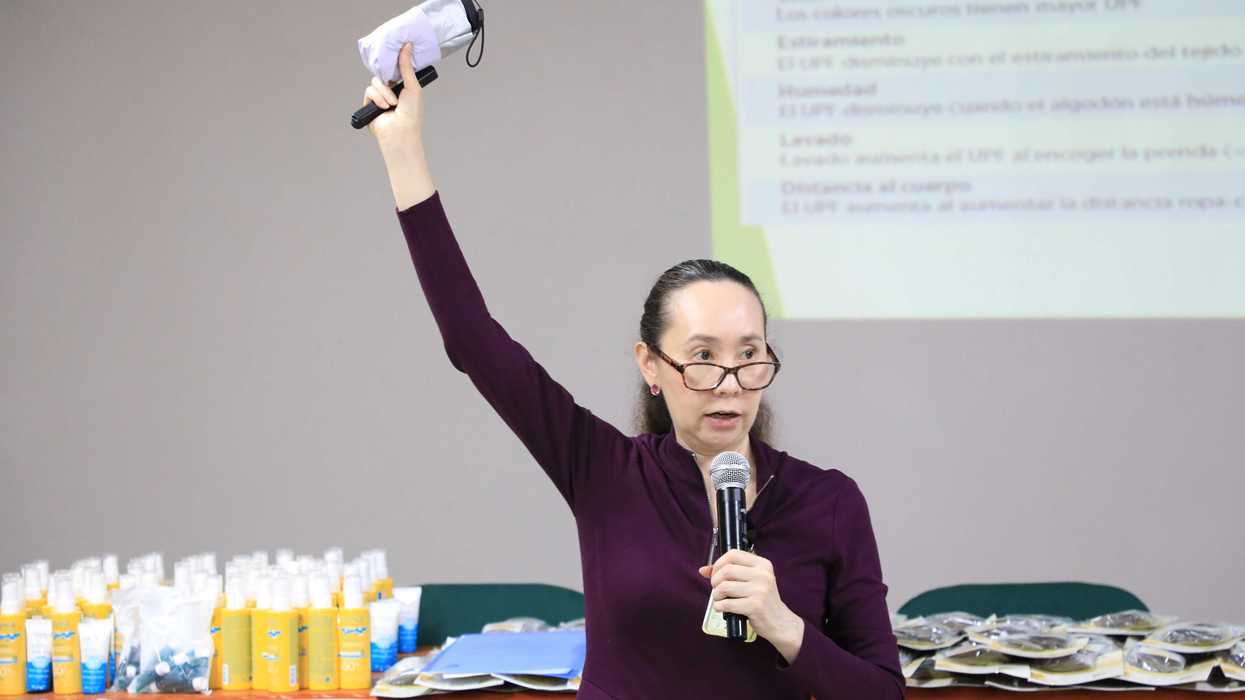 Especialista del IMSS sostiene una sombrilla UPF mientras explica los factores que modifican la protección de la ropa.
