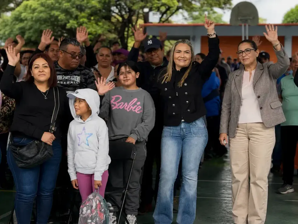 Familias y autoridades levantan la mano durante la inauguraci\u00f3n del curso de verano en una cancha escolar