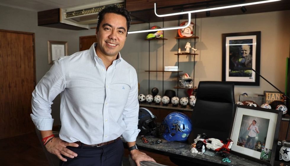 Felifer Mac\u00edas Olvera, presidente municipal de Quer\u00e9taro, posa junto a su escritorio, con cascos, balones y objetos deportivos al fondo.
