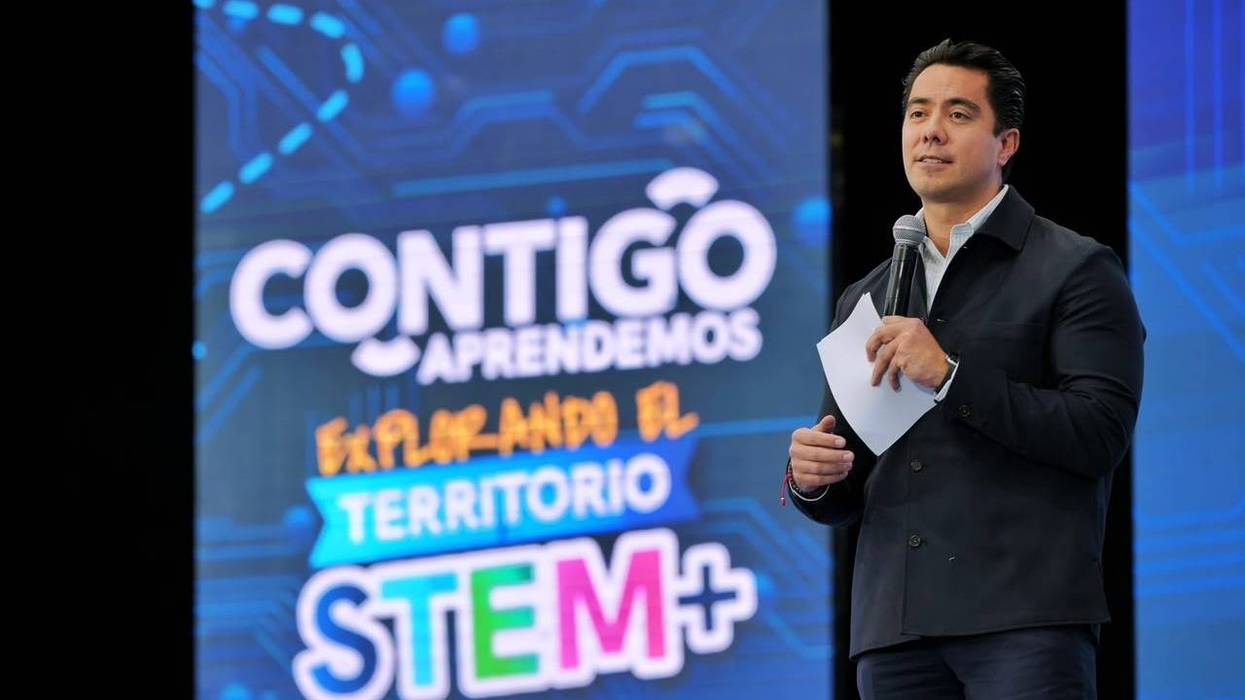 Felifer Macías habla con micrófono ante la pantalla de Contigo Aprendemos Explorando el Territorio STEM+, Querétaro