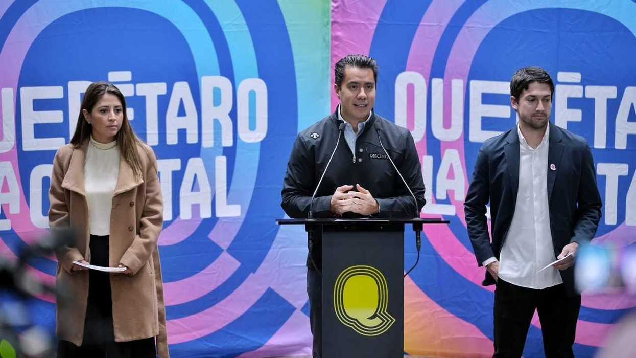 Felifer Macías habla en un podio con el logotipo Q, acompañado por una mujer y un hombre, frente a un fondo de Querétaro