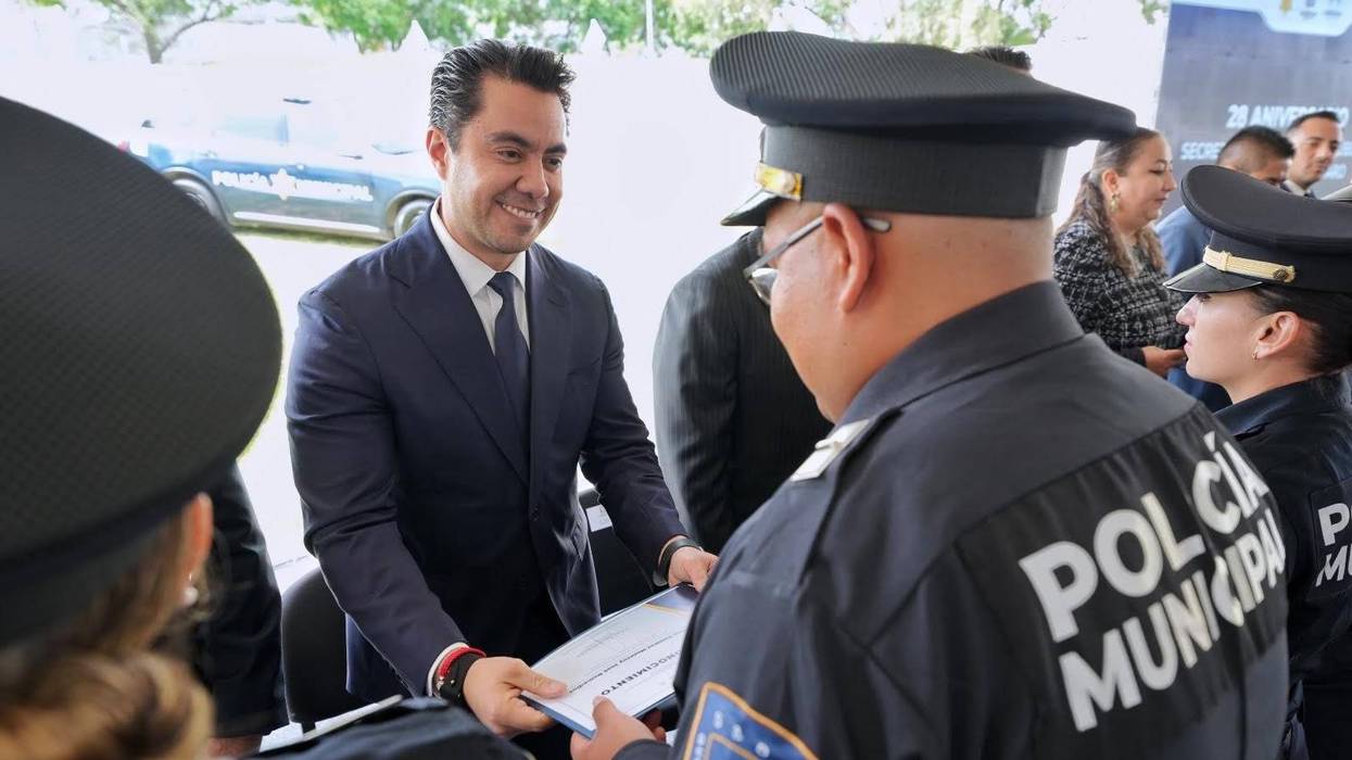 Felipe Fernando Macías Olvera entrega un reconocimiento a un elemento de la Policía Municipal de Querétaro durante una ceremonia de la corporación