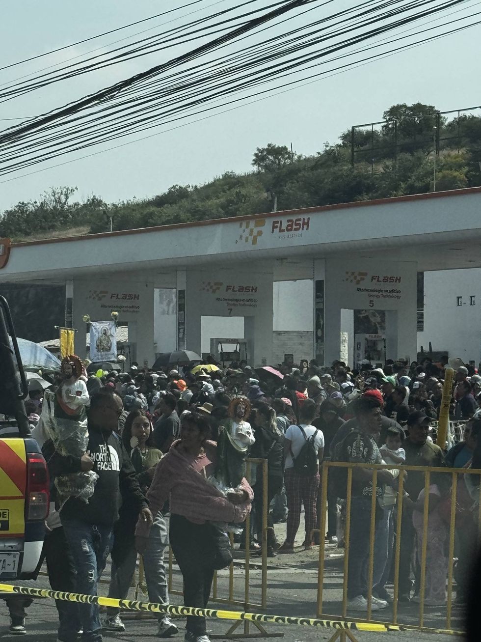 Fieles, algunos con im\u00e1genes de San Judas Tadeo en brazos, se concentran detr\u00e1s de vallas met\u00e1licas frente a una gasolinera durante la festividad en La Noria, El Marqu\u00e9s.