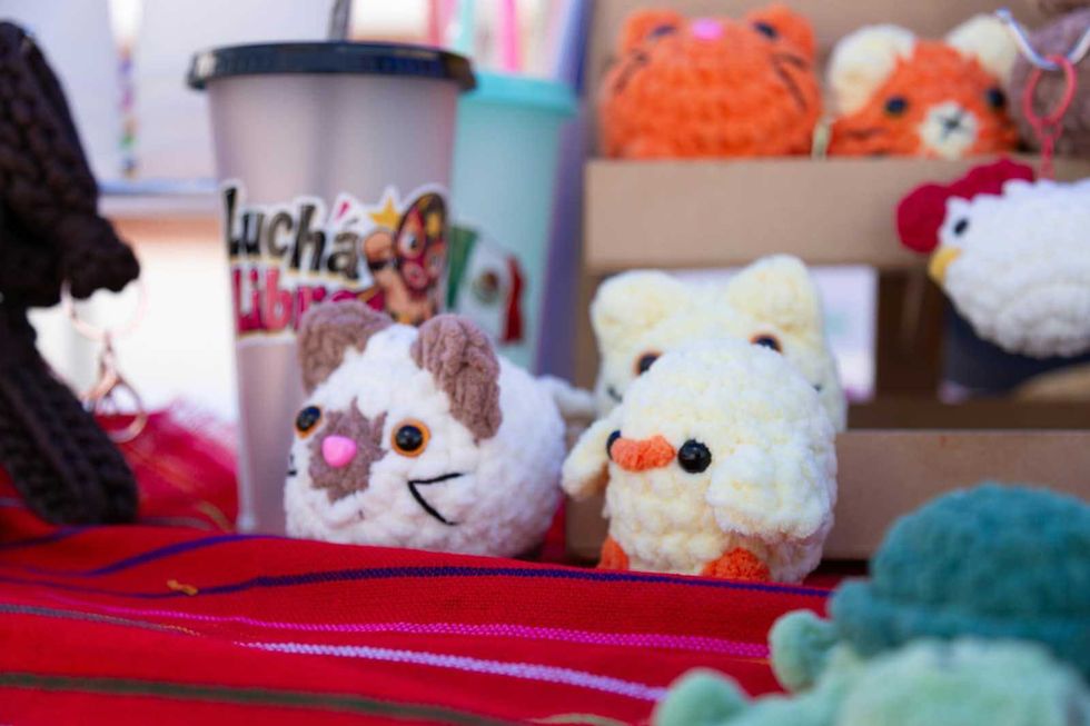Figuras tejidas de estambre con forma de animales y un vaso con la leyenda Lucha Libre, en un puesto del Paseo Dominical en La Llave.