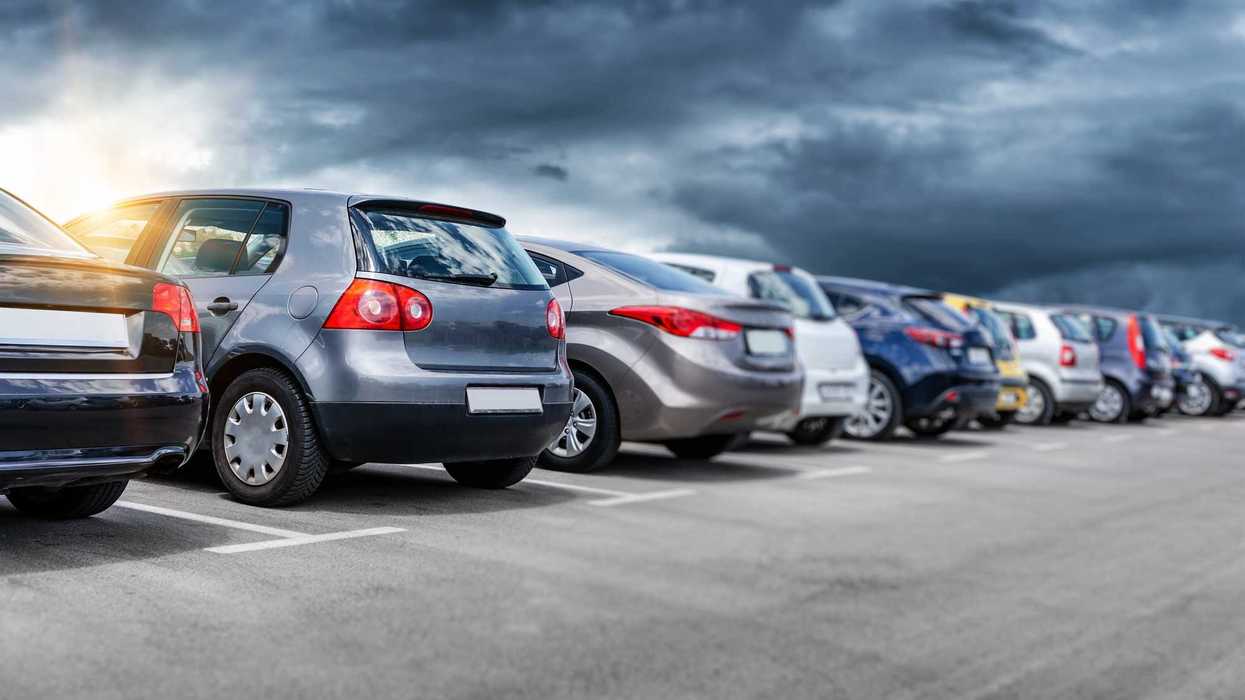 Fila de automóviles estacionados en un lote de venta de vehículos bajo cielo nublado
