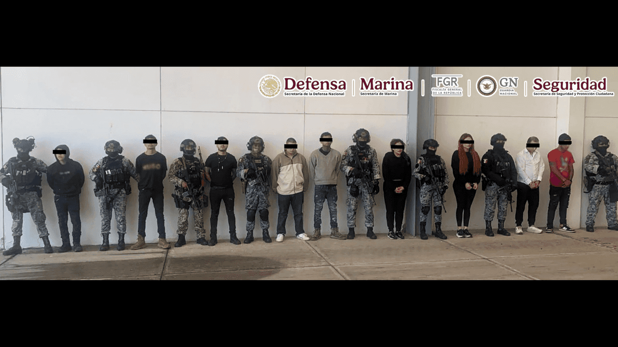 Fila de personas detenidas con el rostro cubierto, custodiadas por elementos de seguridad, durante operativo contra célula delictiva en Michoacán.