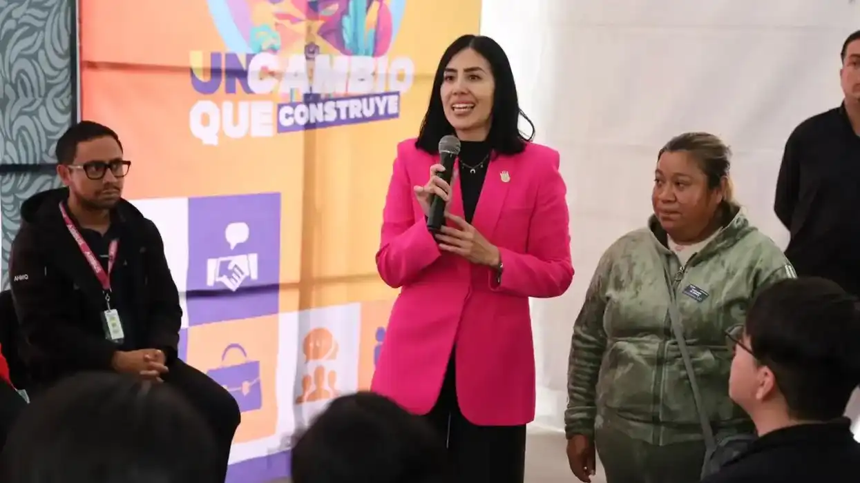 Funcionaria con saco rosa habla con micrófono ante asistentes durante la Feria de Empleo Colón 2026