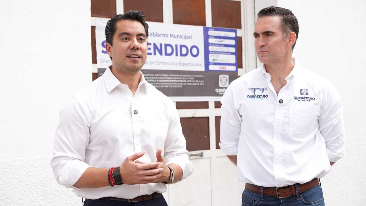 Funcionarios municipales frente al sello de clausura de empresa inmobiliaria en Querétaro