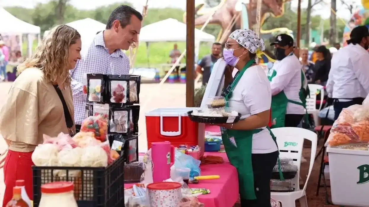 Funcionarios municipales y trabajadoras del festival posan con platillos en un stand patrocinado por Boing