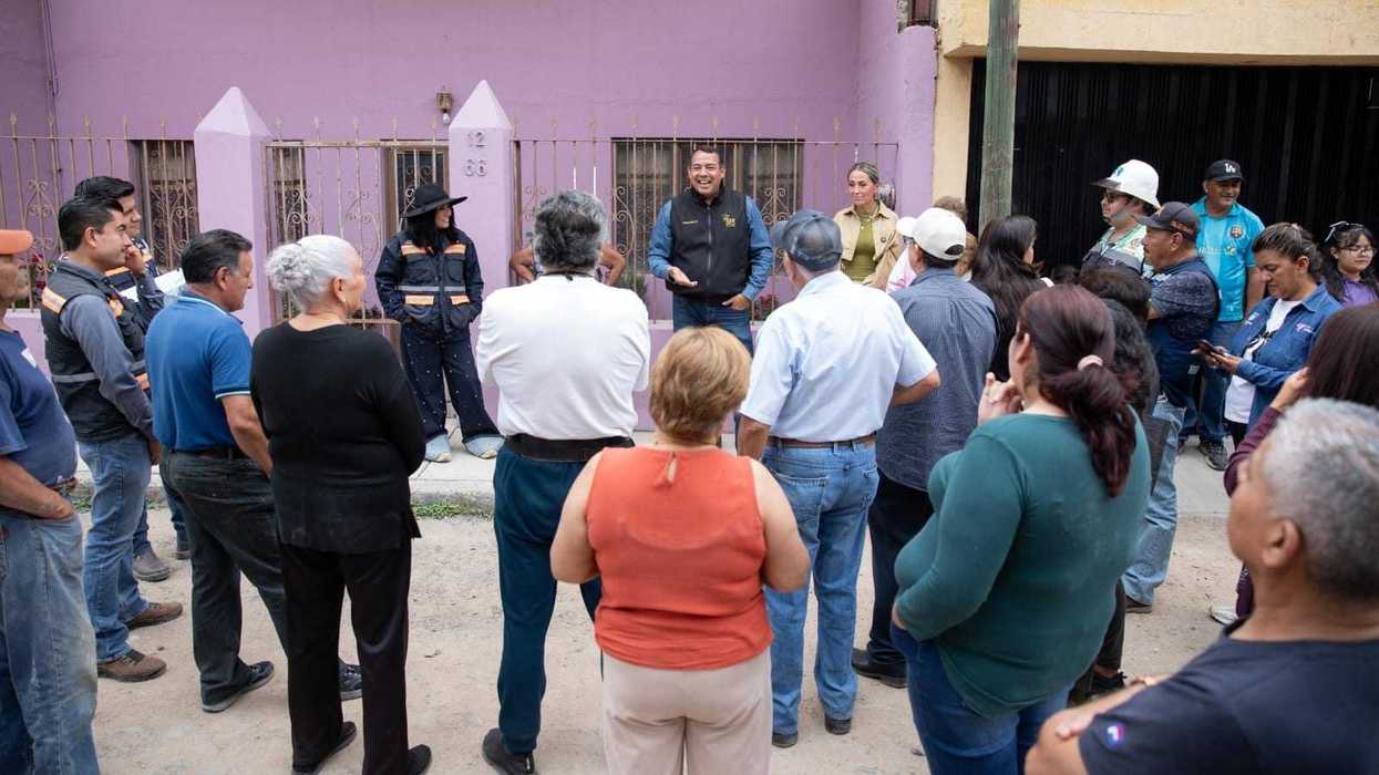 Funcionarios y vecinos reunidos en calle de tierra de colonia Indeco durante arranque de obra