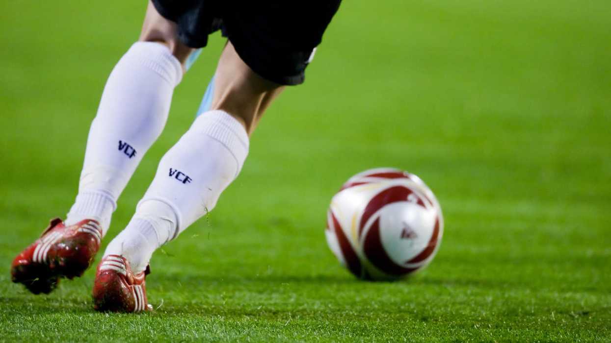 Futbolista con calcetas blancas y tachones rojos conduce el balón sobre el césped durante un partido, imagen de nota sobre turismo deportivo de mexicanos en Madrid