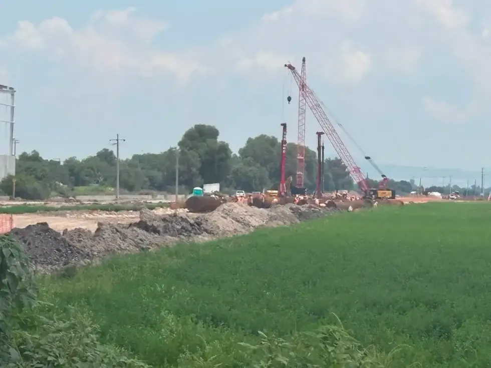 Gr\u00faas y maquinaria pesada en obra del tren M\u00e9xico-Quer\u00e9taro cerca del camino bloqueado