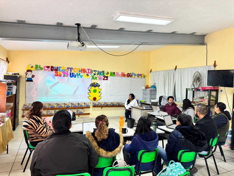 Grupo de docentes y directivos trabajan en una sesi\u00f3n del CTE en el interior de un aula de educaci\u00f3n primaria, con proyecci\u00f3n en pantalla