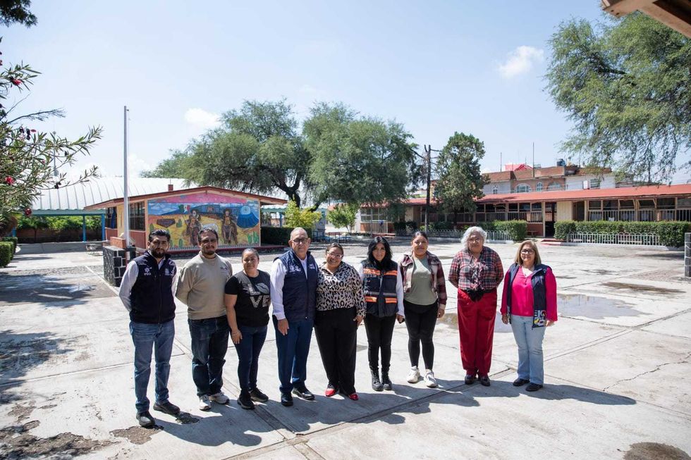 Grupo de funcionarios y personal educativo en el patio de una escuela de San Juan del R\u00edo.