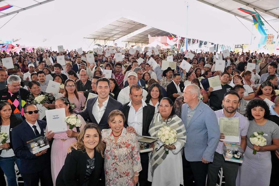 Grupo de parejas, funcionarios y asistentes levantan sus actas de matrimonio al finalizar la ceremonia colectiva en el Estadio Corregidora.