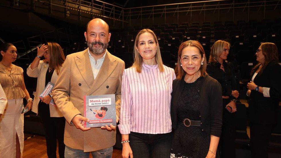 Grupo de personas sostiene el libro "Mam\u00e1, Pap\u00e1: Me hiciste Adicto" en un teatro