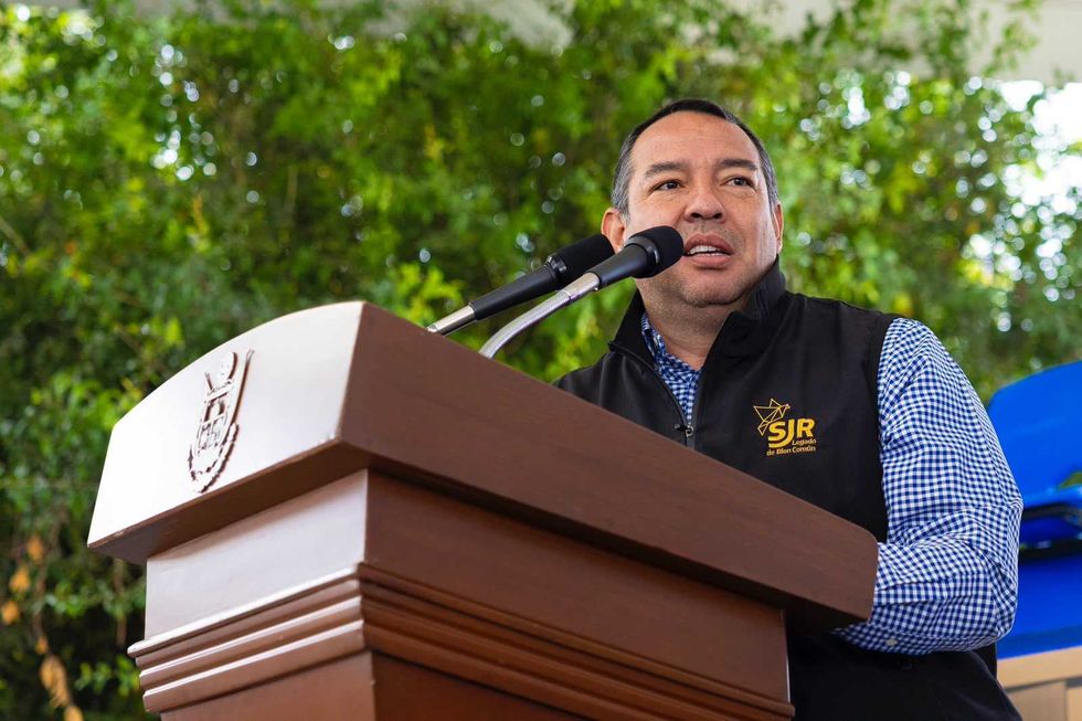 Hombre con chamarra negra habla ante un micr\u00f3fono en el podio durante la entrega del arcotecho en Loma Linda