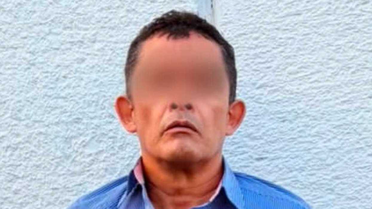 Hombre con rostro difuminado, vestido con camisa azul, detenido por policías de El Marqués tras hallarle un arma de fuego.