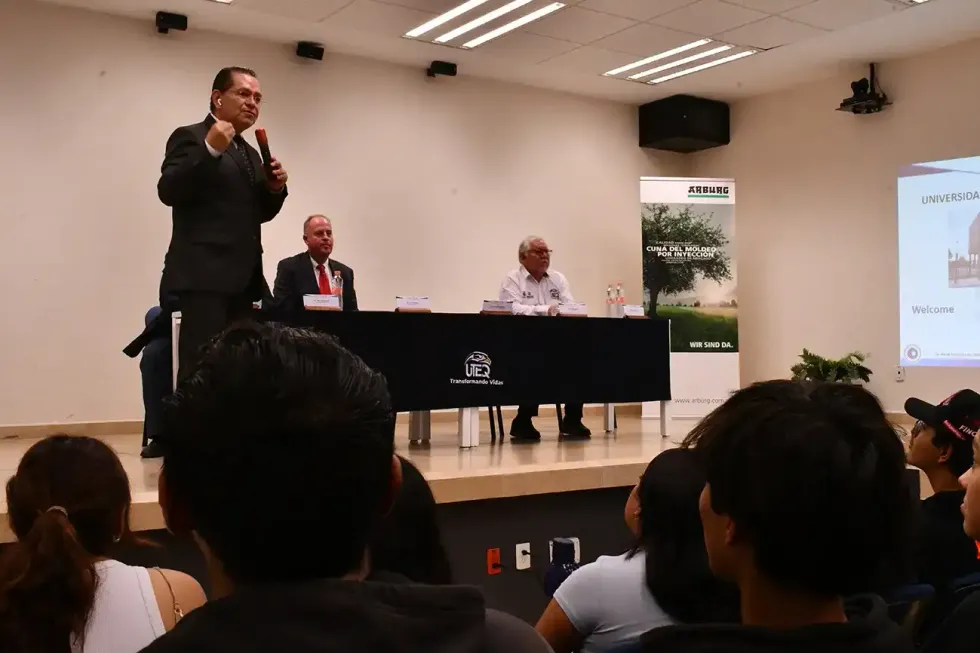 Hombre con traje oscuro habla frente a un banner de ARBURG durante el evento de firma del convenio con la UTEQ en Quer\u00e9taro.