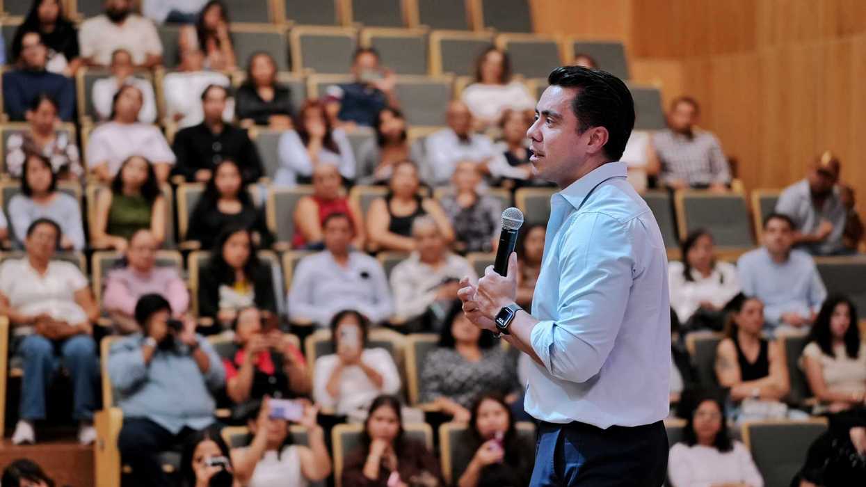 Hombre de camisa azul claro habla con un micrófono ante el público del auditorio durante la entrega de las Becas Vive México en Querétaro