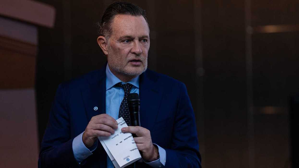 Hombre de traje azul con micrófono y una tarjeta en las manos; declaraciones sobre el documental de HBO del 5M en Querétaro
