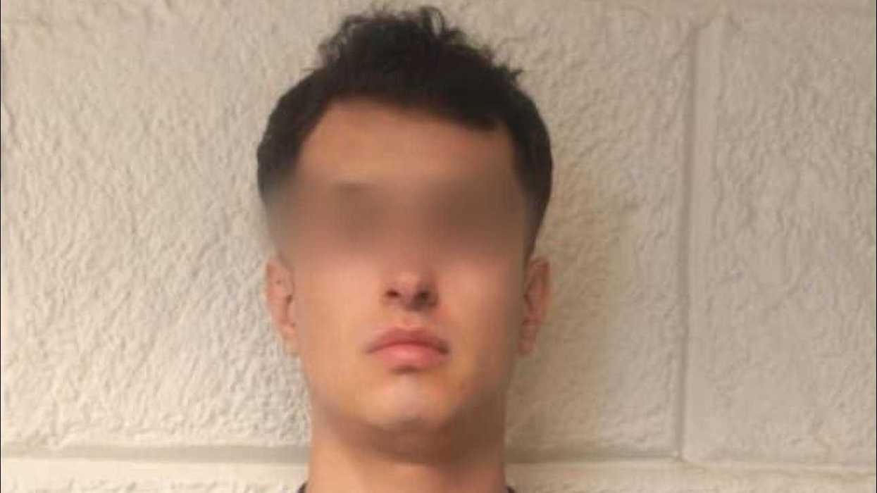 Hombre joven de cabello oscuro y corto, rostro difuminado, fotografiado de frente contra un muro de block color claro; viste playera deportiva tipo Barcelona con franjas azules y granates.