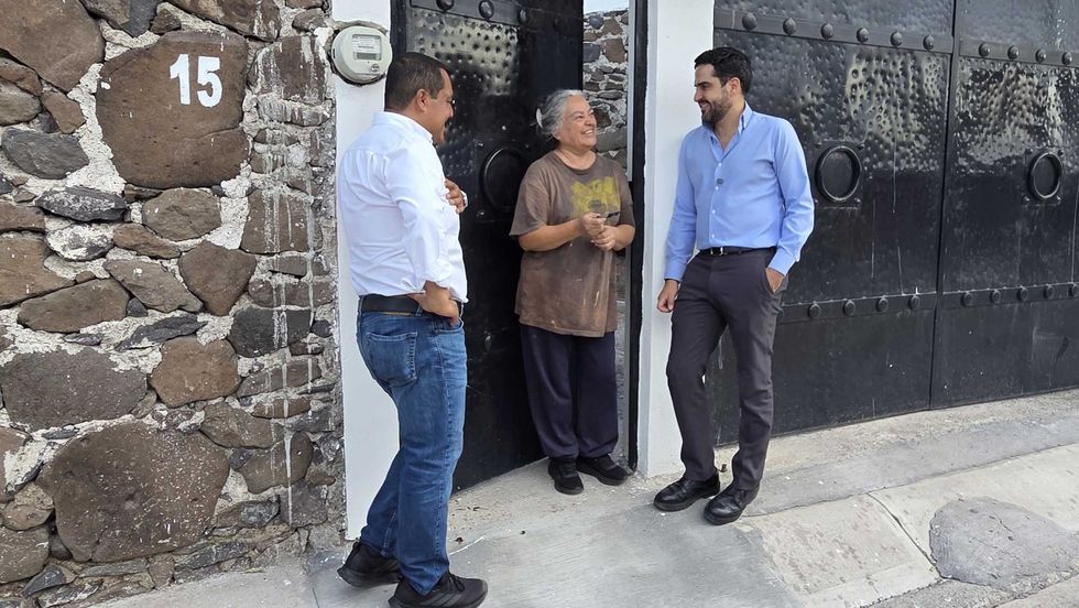hombres conversan con una vecina en la puerta de su domicilio