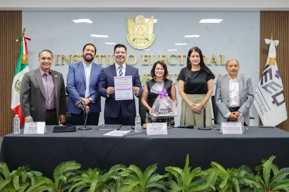 Hugo Molina Mart\u00ednez sostiene un reconocimiento durante el evento del IEEQ.