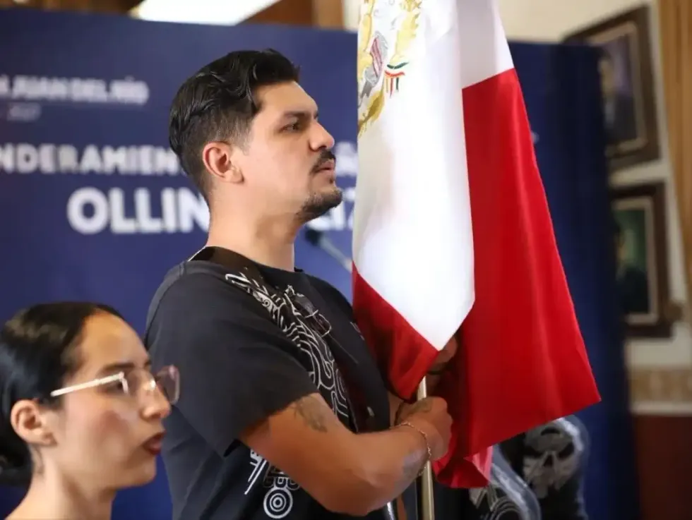 Integrante del Grupo de Danza Ollin Yoliztli porta la bandera nacional