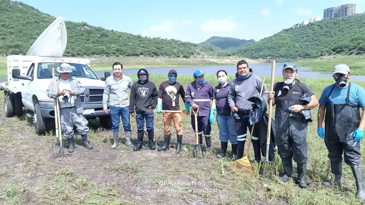 Integrantes de la brigada de limpieza posan con herramientas a la orilla de la presa El Batán, en Corregidora.