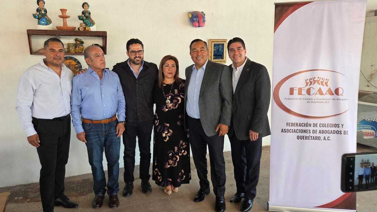 Integrantes de la Federación de Colegios y Asociaciones de Abogados de Querétaro posan en evento junto a lona institucional