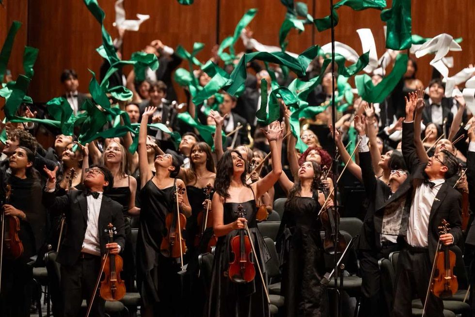 Integrantes de la Orquesta Sinf\u00f3nica Infantil de M\u00e9xico celebran el cierre de su 34.\u00aa gira nacional lanzando cintas al aire en el Palacio de Bellas Artes.