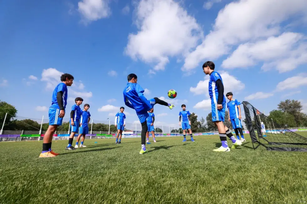 J\u00f3venes participantes de la Cl\u00ednica de F\u00fatbol INDEREQ 2026 practican ejercicios de control y pase en la cancha de la unidad deportiva de Quer\u00e9taro, bajo cielo despejado.