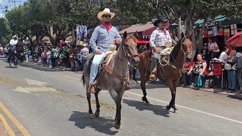 jinetes avanzan a caballo por una calle de San Juan del R\u00edo durante la Cabalgata de la Amistad.