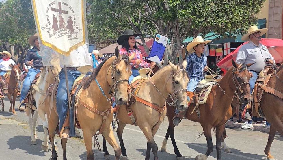 jinetes avanzan a caballo por una calle de San Juan del R\u00edo durante la Cabalgata de la Amistad.