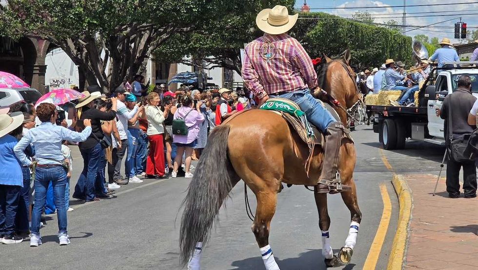 jinetes avanzan a caballo por una calle de San Juan del R\u00edo durante la Cabalgata de la Amistad.