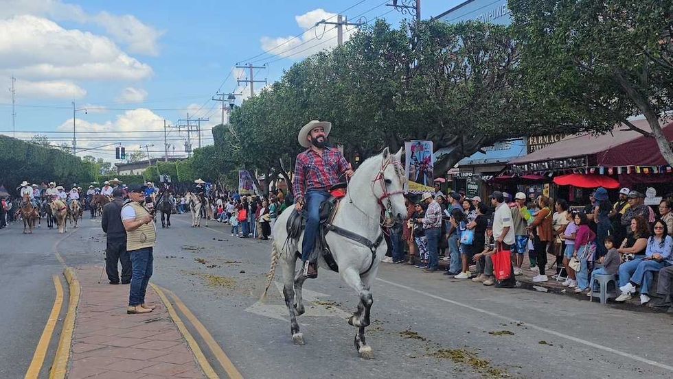 jinetes avanzan a caballo por una calle de San Juan del R\u00edo durante la Cabalgata de la Amistad.