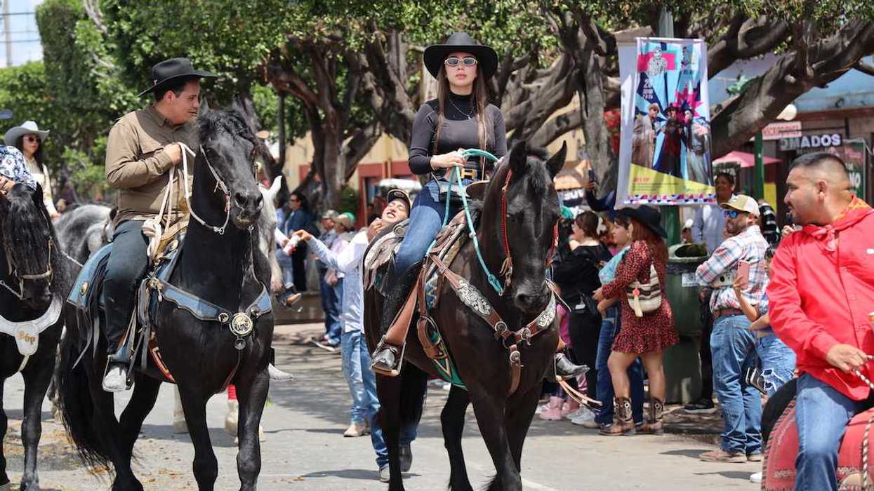 jinetes avanzan a caballo por una calle de San Juan del Río durante la Cabalgata de la Amistad.