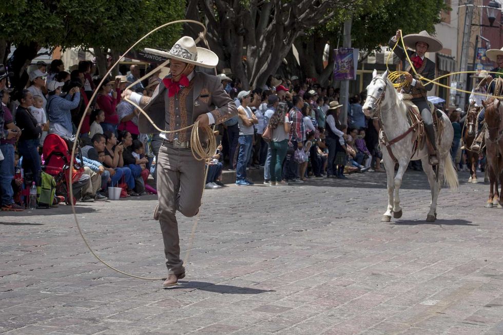 Jinetes con traje charro avanzan en grupo por una avenida del Centro de San Juan del R\u00edo durante la Cabalgata de la Amistad.