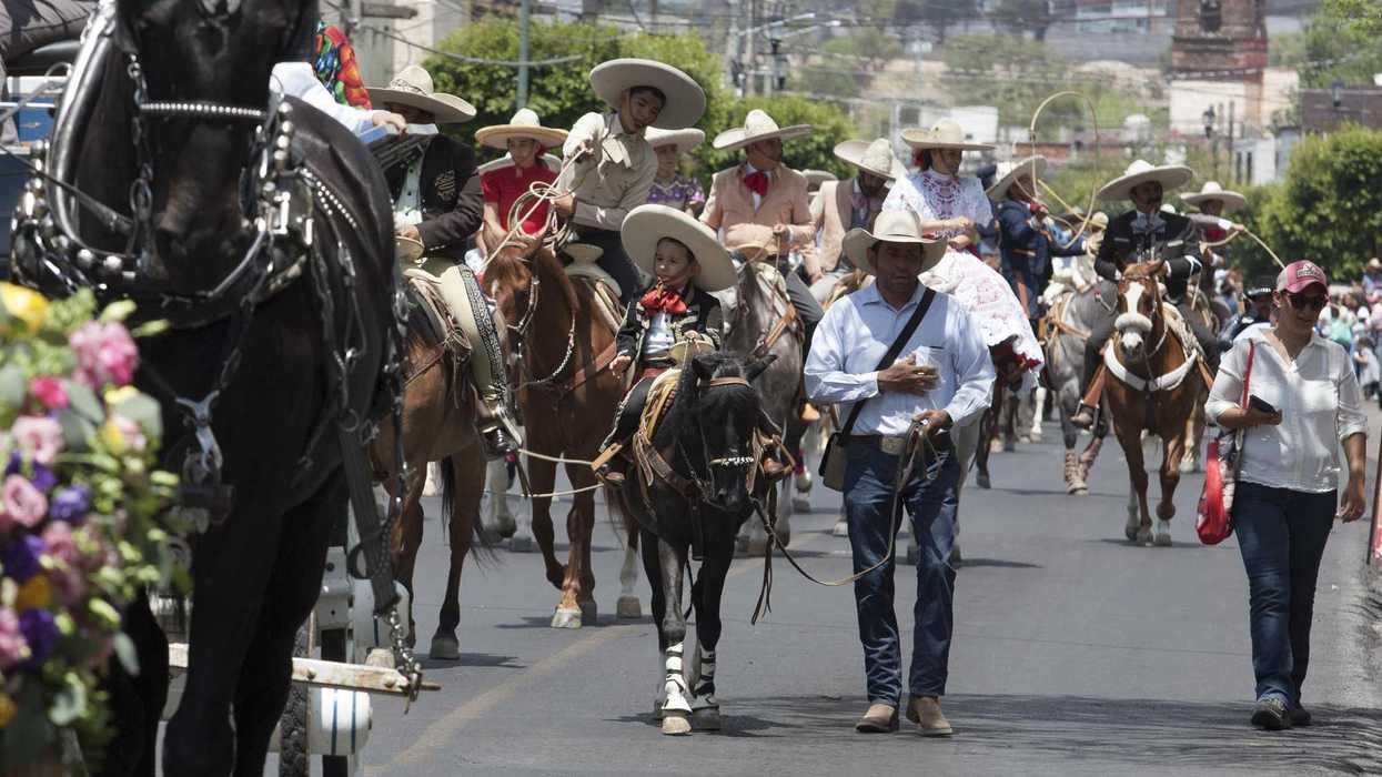 Jinetes con traje charro avanzan en grupo por una avenida del Centro de San Juan del Río durante la Cabalgata de la Amistad.