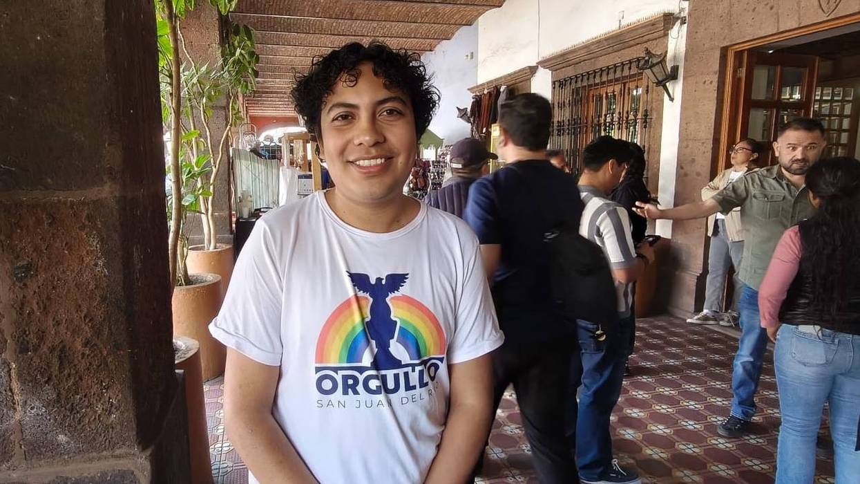Joven con playera del colectivo Orgullo San Juan del Río, bajo un portal durante la rueda de prensa sobre la Ley de Identidad de Género en San Juan del Río.