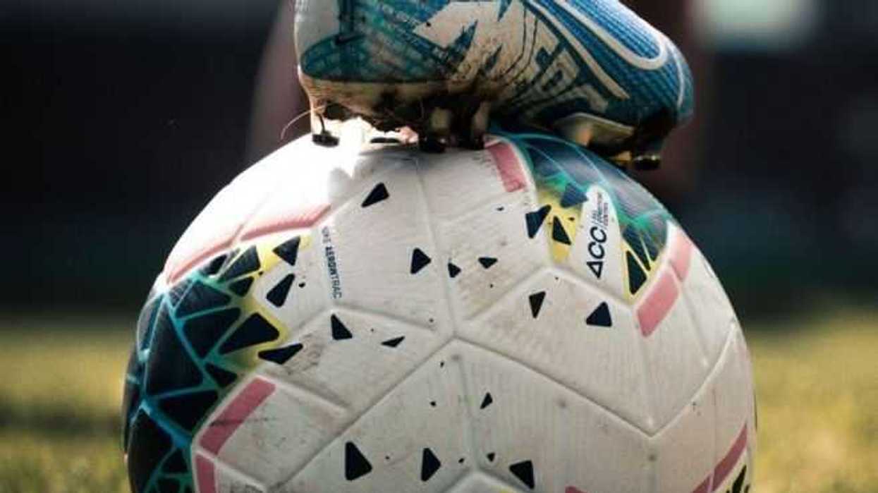 Jugador con pie arriba de balon de futbol